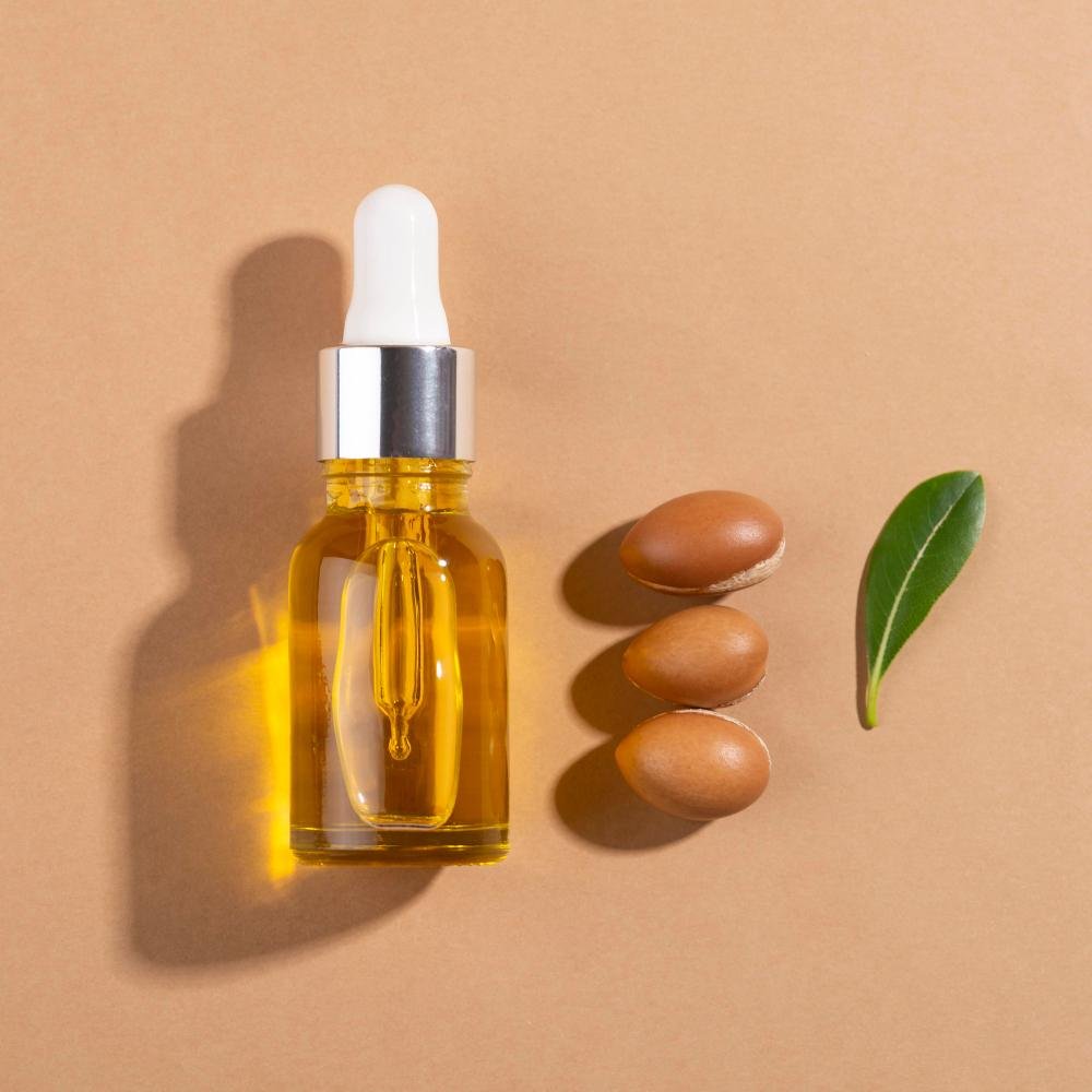 Flacon compte-gouttes d'huile d'argan dorée posé à côté de noix d'argan