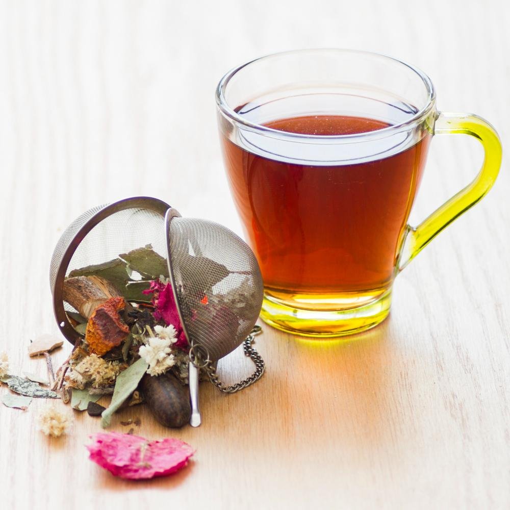 Tasse d'infusion de plantes avec boule à thé et fleurs séchées